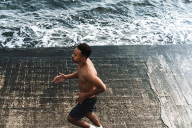 Genç Afrikalı sporcu, deniz kenarında koşuyor. Egzersiz yapıyor..