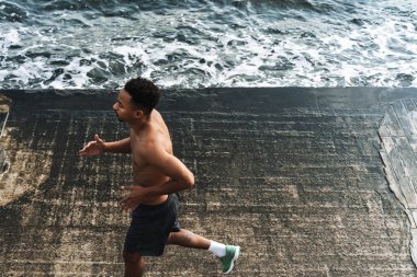 Genç Afrikalı sporcu, deniz kenarında koşuyor. Egzersiz yapıyor..