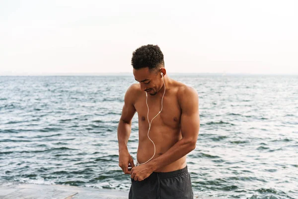 Bonito jovem homem de esportes africanos ao ar livre na praia mar andando fazer exercícios . — Fotografia de Stock