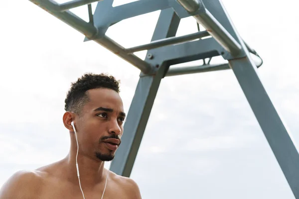 Olahraga muda afrika yang tampan dan kuat di luar ruangan di pantai berjalan kaki membuat latihan mendengarkan musik dengan earphone . — Stok Foto