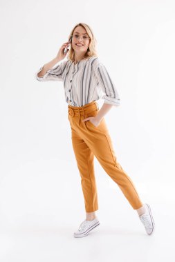 Cep telefonu yürürken ve konuşurken gözlük takan gülümseyen sarışın kadın tam uzunlukta fotoğraf