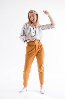 Earpods üzerinden müzik dinlerken dans ve cep telefonu tutan güzel kadın tam uzunlukta fotoğraf