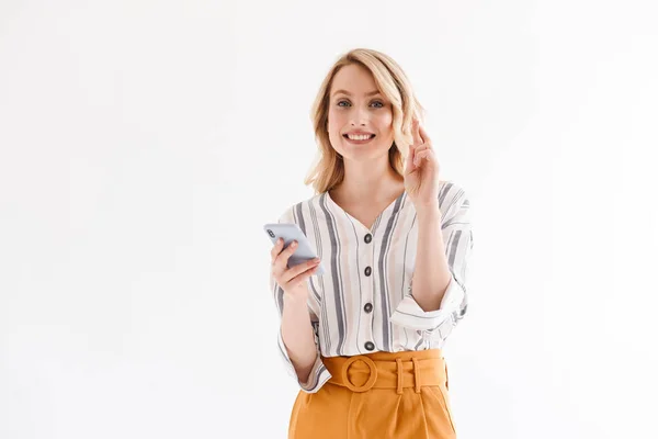 Fotografie usměvavé blondýny v příležitostných šatech, držící smartphone a překřížené prsty — Stock fotografie