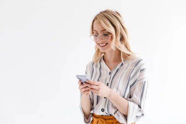 Fotó az optimista, vonzó nőt visel szemüveget mosolyogva a telefon és a gépelés — Stock Fotó