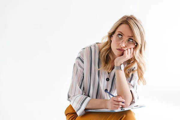 Photo of blond serious woman wearing glasses propping her head and looking upward while sitting — Stock Photo, Image
