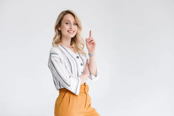 Ritratto a metà giro di giovane donna che indossa abiti casual sorridendo alla fotocamera e puntando il dito verso l'alto — Foto Stock