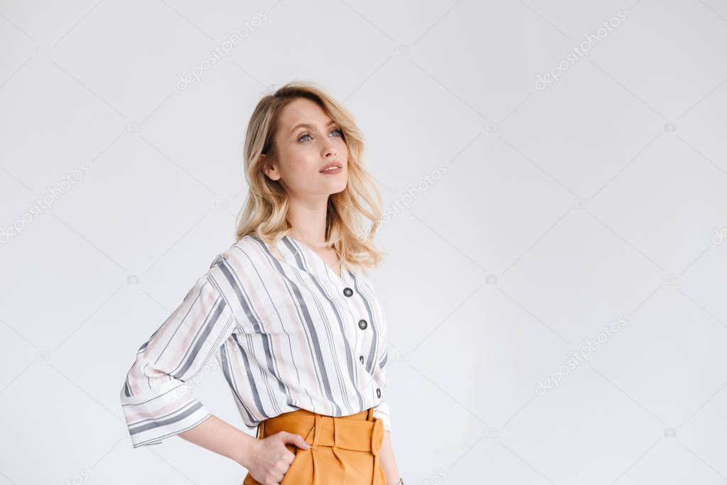 Half turn portrait of young nice woman wearing casual clothes looking aside at copyspace with hand in her pocket