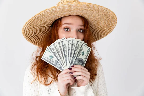 Junges nettes Mädchen Rotschopf posiert isoliert über weiße Wand Hintergrund trägt Hut hält Geld. — Stockfoto
