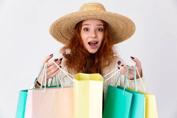 Young excited emotional cute girl redhead posing isolated over white wall background holding shopping bags. — Zdjęcie stockowe