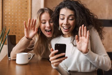 Kafede oturan iki neşeli genç kız arkadaş