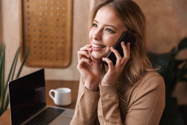 Kafede oturan oldukça duygusal mutlu kız cep telefonu ile konuşurken.