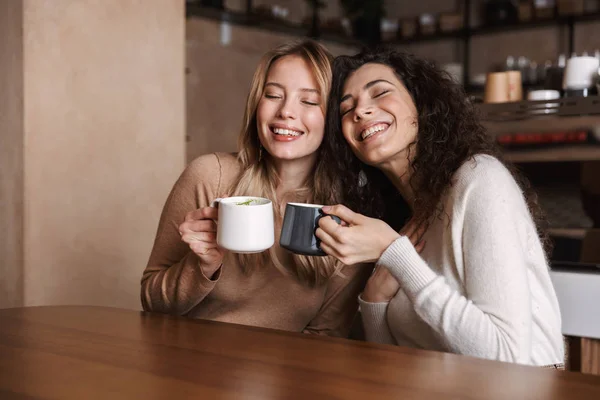 Chicas felices amigos sentados en la cafetería hablando entre sí beber té o café . —  Fotos de Stock