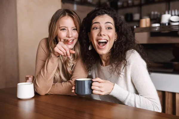 Счастливые девушки друзья сидят в кафе, разговаривают друг с другом, пьют чай или кофе. . — стоковое фото