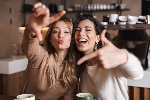 Två glada unga flickor vänner sitter vid Café bordet — Stockfoto