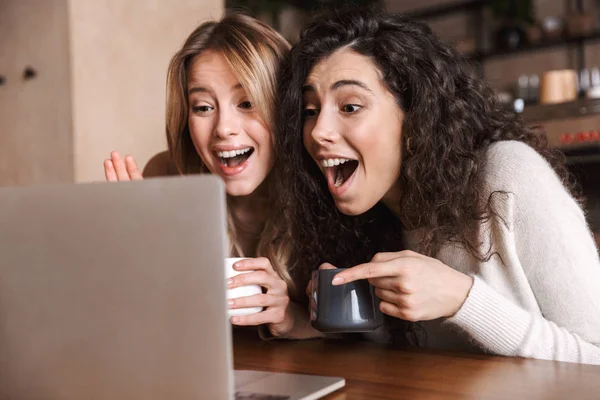 Дві веселі молоді дівчата друзі сидять за столом кафе — стокове фото