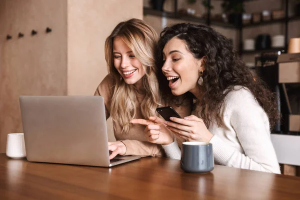 Duygusal şok kız arkadaşlar dizüstü bilgisayar kullanarak kafede oturan. — Stok fotoğraf