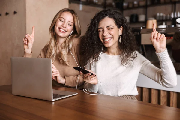 Two cheerful young girls friends sitting at the cafe table — Stock Photo, Image