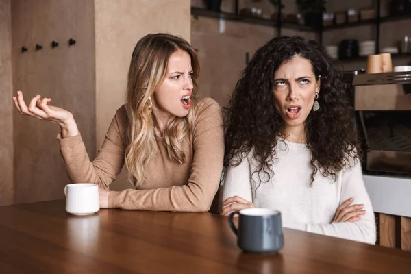 Missnöjd skrikande gräl unga vackra flickor vänner sitter i kaféet. — Stockfoto