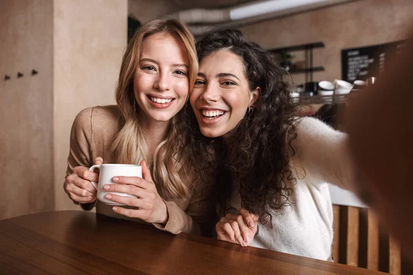 Eccitato felice belle ragazze amici seduti in caffè prendere un selfie dalla fotocamera . — Foto Stock