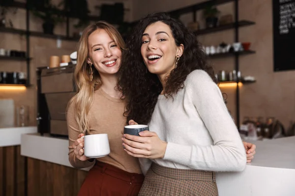 Två glada unga flickvänner som står på caféet — Stockfoto
