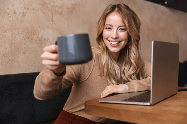 Chica bastante feliz sentado en la cafetería con ordenador portátil . — Foto de Stock