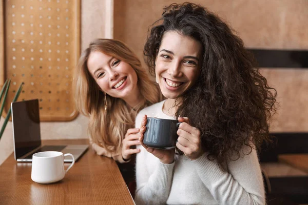 Två glada unga flickvänner sitter på caféet — Stockfoto