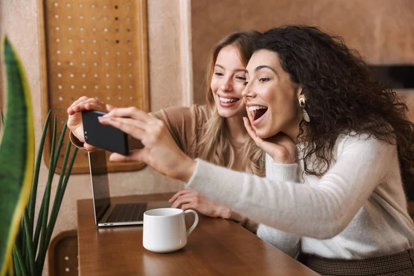 Zwei fröhliche junge Freundinnen sitzen im Café — Stockfoto