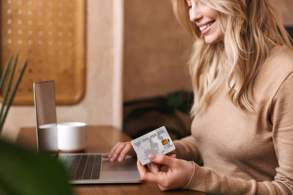 Kafede dizüstü bilgisayar kullanarak kredi kartı tutan oturan güzel kız Kırpılmış görüntü. — Stok fotoğraf
