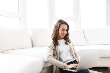 Dizüstü bilgisayarda çalışan güzel genç bir kadın.