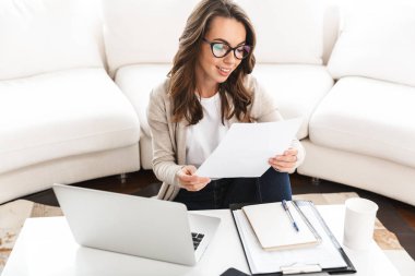 Dizüstü bilgisayarda çalışan güzel genç bir kadın.