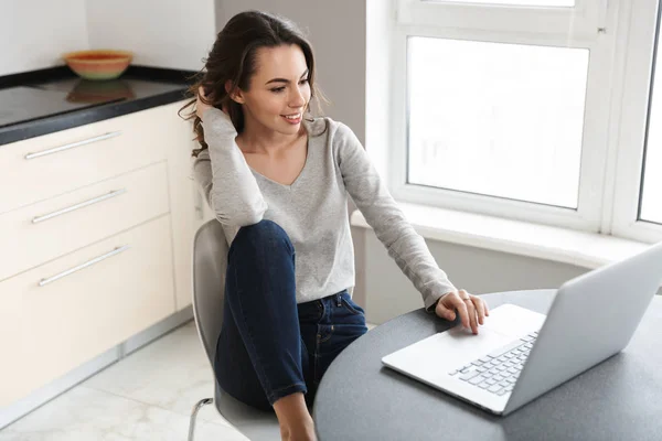 Aantrekkelijke lachende jonge vrouw werkt op laptop — Stockfoto