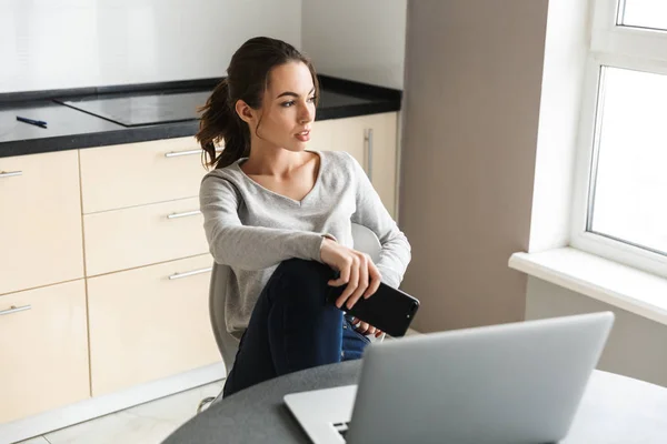 Attractive smiling young woman working on laptop
