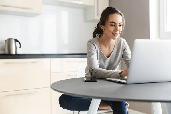 Aantrekkelijke lachende jonge vrouw werkt op laptop — Stockfoto