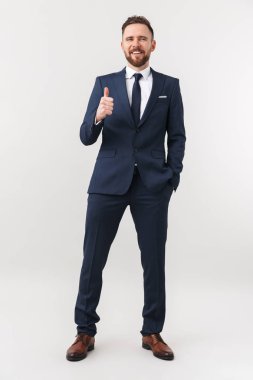 Yakışıklı genç işadamı başparmak gösteren beyaz duvar arka plan üzerinde izole poz.