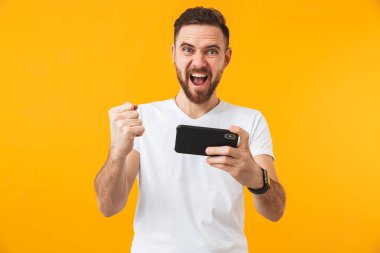 Hhappy adam telefonla sarı duvar arka plan üzerinde izole poz oyunları.