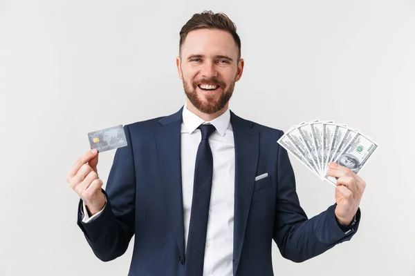 Young businessman posing isolated over white wall background holding credit card and money. — Stock Photo, Image