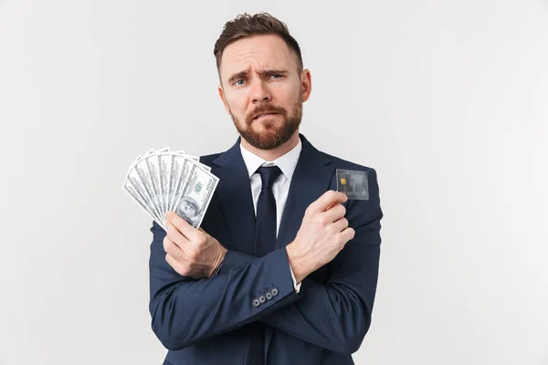 Young businessman posing isolated over white wall background holding credit card and money. — Stock Photo, Image