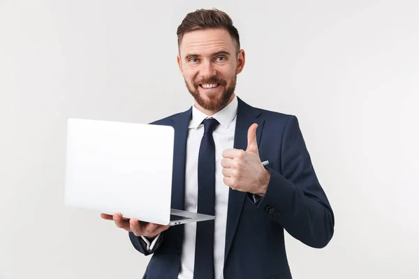 Emocionado empresario posando aislado sobre fondo blanco de la pared sosteniendo ordenador portátil . — Foto de Stock