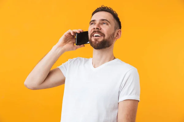 Gelukkige man poseren geïsoleerd over gele muur achtergrond praten via de telefoon. — Stockfoto