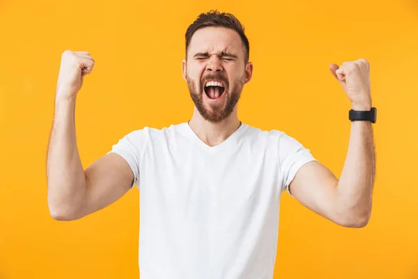 Man poseren geïsoleerd over gele muur achtergrond maken winnaar gebaar. — Stockfoto