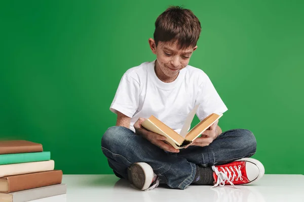 Schattige kleine jongen met sproeten studeren met stapel boeken — Stockfoto