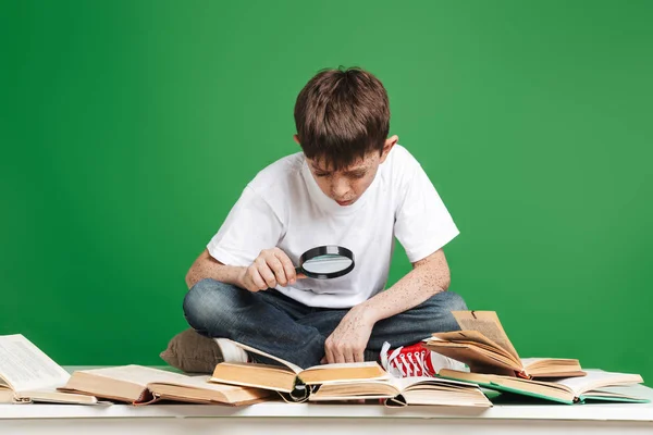 Schattige kleine jongen met sproeten studeren met stapel boeken — Stockfoto