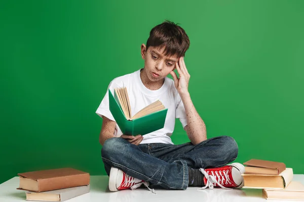 Schattige kleine jongen met sproeten studeren met stapel boeken — Stockfoto