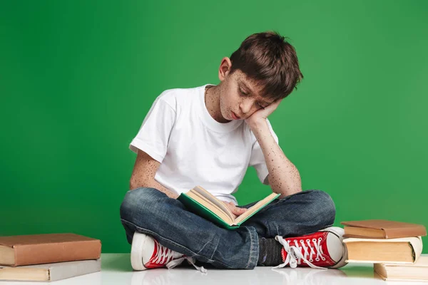 Schattige kleine jongen met sproeten studeren met stapel boeken — Stockfoto