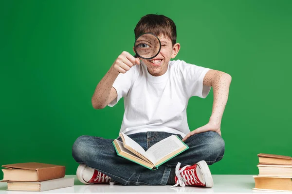 Schattige kleine jongen met sproeten studeren met stapel boeken — Stockfoto