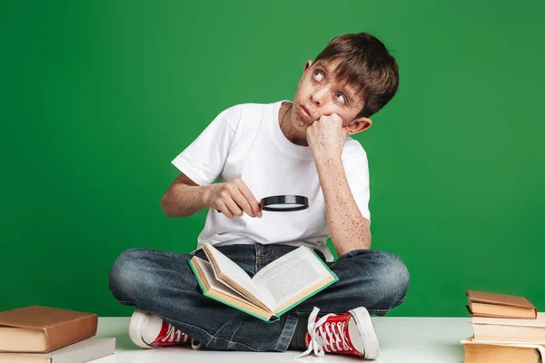 Schattige kleine jongen met sproeten studeren met stapel boeken — Stockfoto