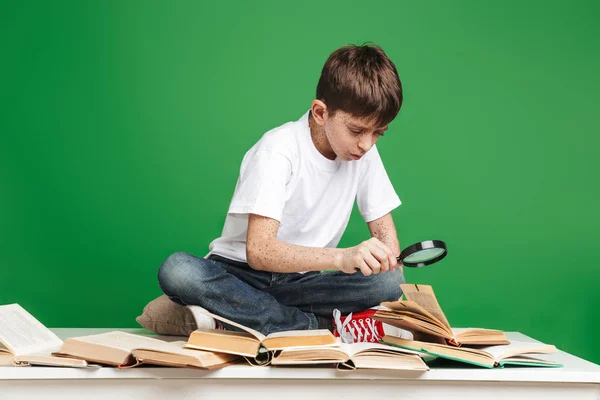 Netter kleiner Junge mit Sommersprossen, der mit einem Stapel Bücher lernt — Stockfoto