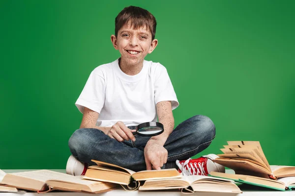 Schattige kleine jongen met sproeten studeren met stapel boeken — Stockfoto