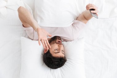 Yatakta yatan yakışıklı bir genç adamın üst görünümü