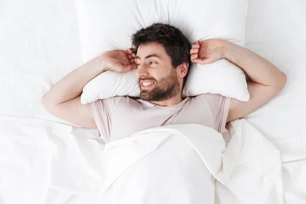 Schöner junger Mann am Morgen Stretching im Bett. — Stockfoto